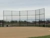 A professional 16-foot tall baseball backstop featuring black vinyl-coated chain-link mesh and a sturdy multi-panel frame