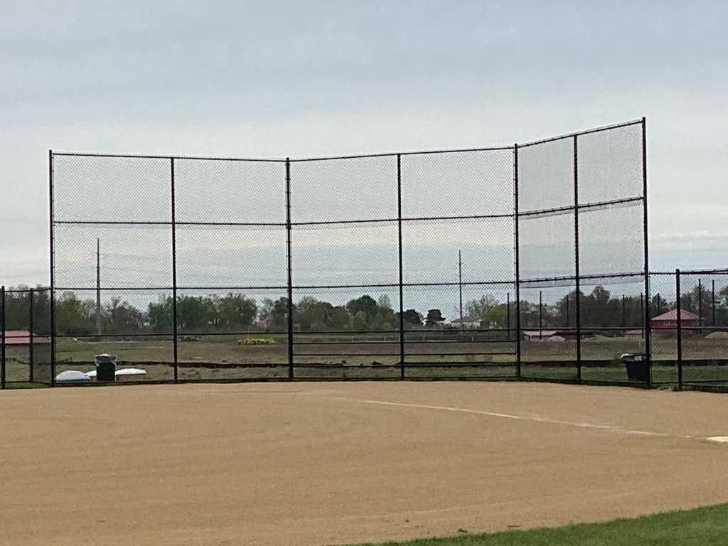 A professional 16-foot tall baseball backstop featuring black vinyl-coated chain-link mesh and a sturdy multi-panel frame
