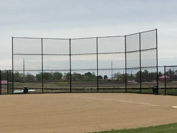 A professional 16-foot tall baseball backstop featuring black vinyl-coated chain-link mesh and a sturdy multi-panel frame