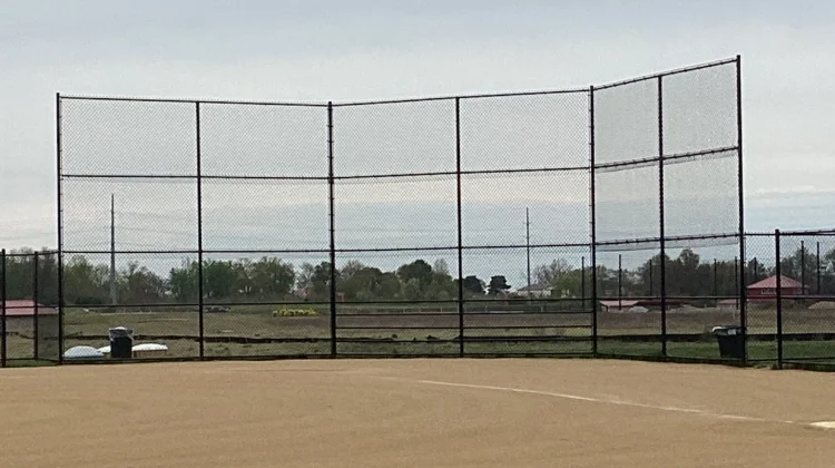 A professional 16-foot tall baseball backstop featuring black vinyl-coated chain-link mesh and a sturdy multi-panel frame