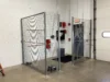 An indoor industrial security cage made of silver welded wire mesh with a double-gated entrance