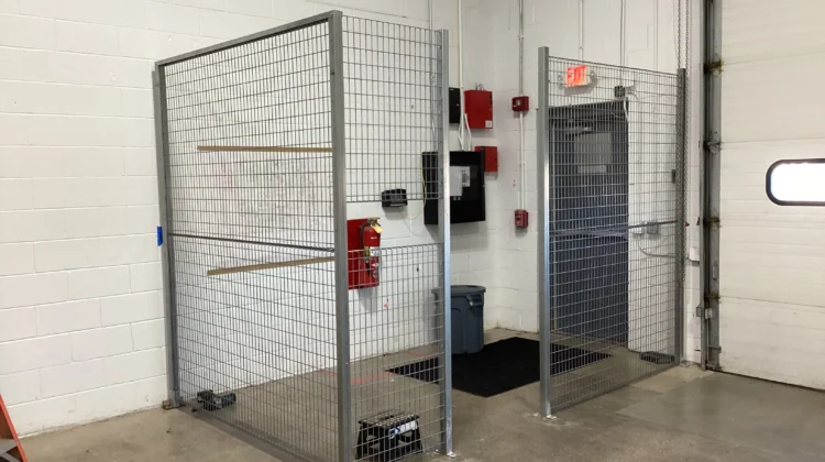 An indoor industrial security cage made of silver welded wire mesh with a double-gated entrance